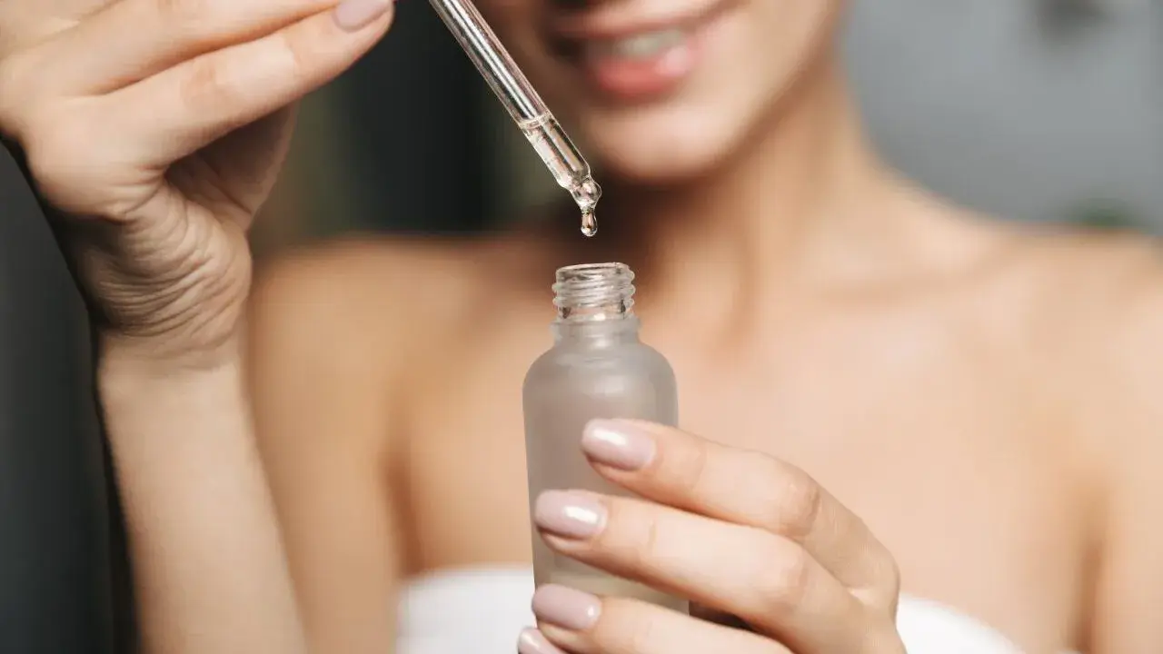 Kobieta aplikuje serum z kwasem fitynowym na twarz. Kwas fitynowy to naturalny antyoksydant.