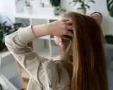 Dziewczyna z długimi, brązowymi włosami delikatnie przeczesuje je dłonią, zastanawiając się, jak zapuścić włosy.