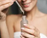 Kobieta aplikuje serum z kwasem fitynowym na twarz. Kwas fitynowy to naturalny antyoksydant.