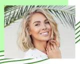 Uśmiechnięta blondynka z falowanymi, cienkimi włosami w stylu long bob, na tle liści palmy.