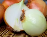 Cebulowy zapach potu unosi się nad koszykiem pełnym świeżych cebul, jedna przekrojona na pół, ukazując białe, soczyste wnętrze.
