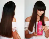 Długie włosy kobiety lśnią dzięki szamponowi Garnier Fructis.