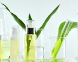 Laboratorium kosmetyczne bada, co to są parabeny. Widać tam buteleczki z kosmetykami, zieleń roślin i szkło laboratoryjne.