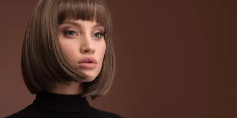 Kobieta z modną fryzurą damską półdługą, w czarnym golfie, z delikatnym makijażem.