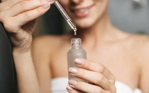 Kobieta aplikuje serum z kwasem fitynowym na twarz. Kwas fitynowy to naturalny antyoksydant.