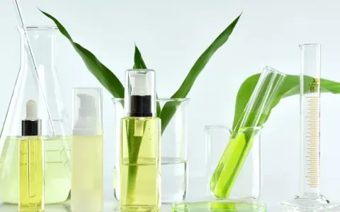 Laboratorium kosmetyczne bada, co to są parabeny. Widać tam buteleczki z kosmetykami, zieleń roślin i szkło laboratoryjne.