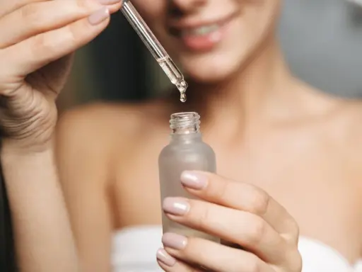 Kobieta aplikuje serum z kwasem fitynowym na twarz. Kwas fitynowy to naturalny antyoksydant.